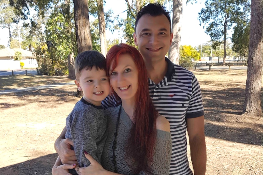 Canditta Natakuapa holds her son next to her husband in the park