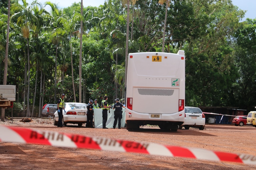 Police tape cordons of a section of carpark with police holding up a sheet