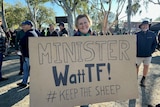 A woman holds a sign saying minister watt TF 
