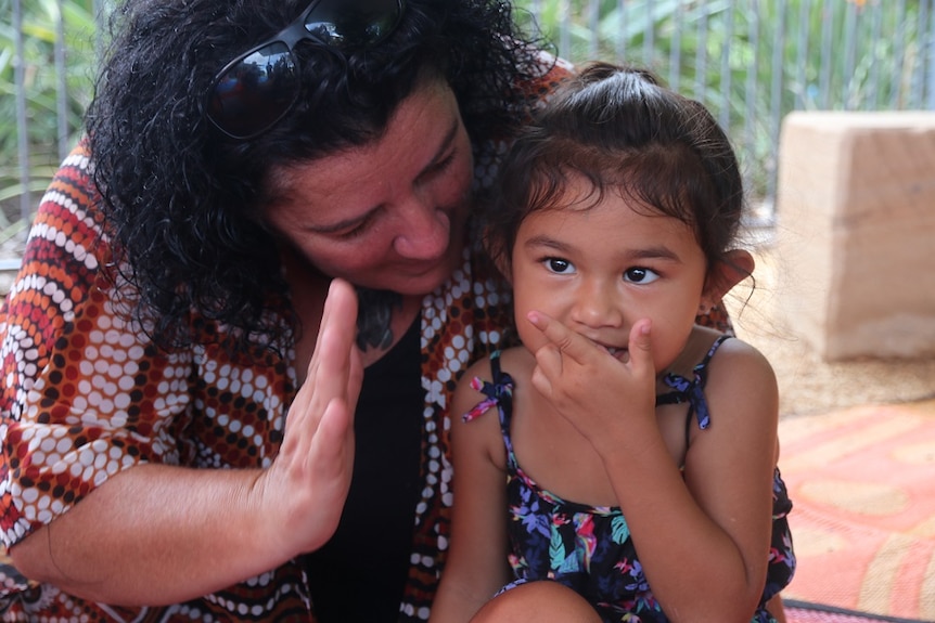 A woman speaks to a child sitting on her lap