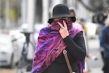 A woman covering her face with a scarf