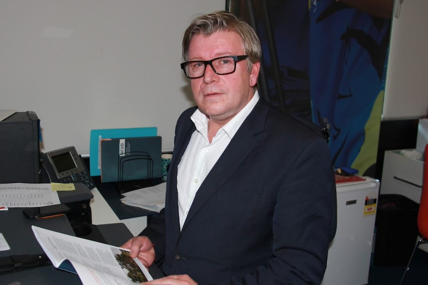 A man in glasses at an office desk.