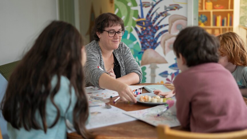 Polly Cousens sits at a table with her children in the Derwent Valley.