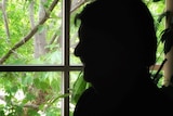 The silhouette of a woman against a backdrop of greenery.