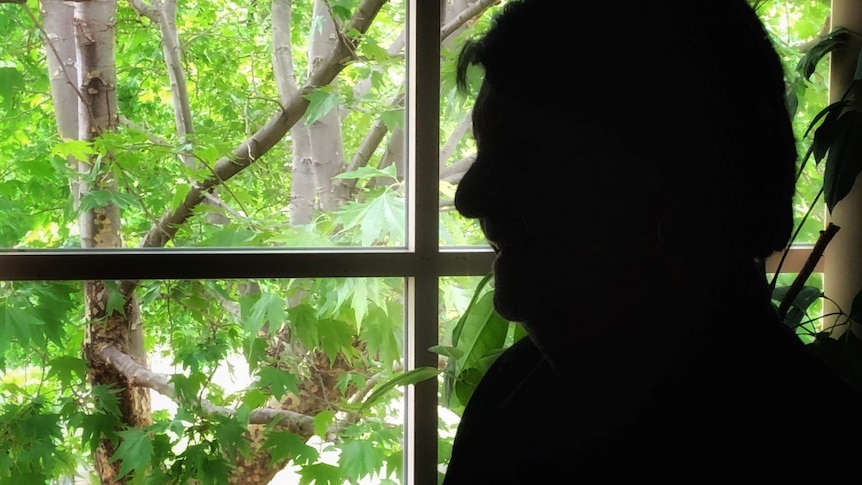 The silhouette of a woman against a backdrop of greenery.