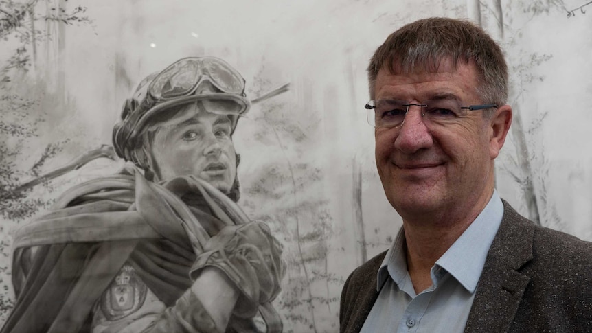 Picture of a man standing next to a charcoal drawing of a firefighter