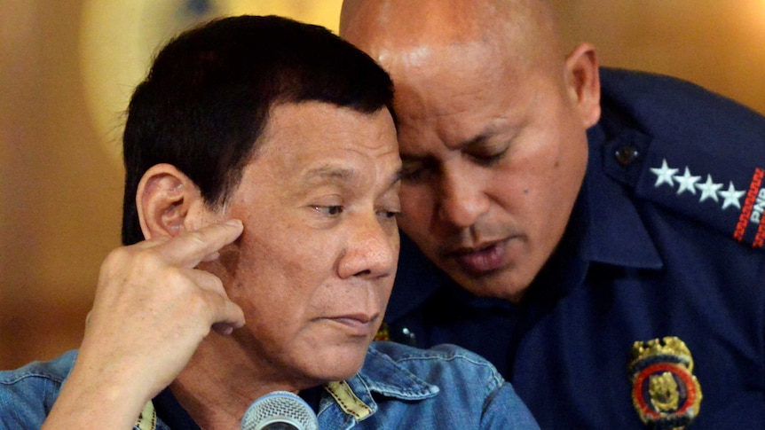 Rodrigo Duterte listens astoPhilippine National Police Director General Ronald Dela Rosa.