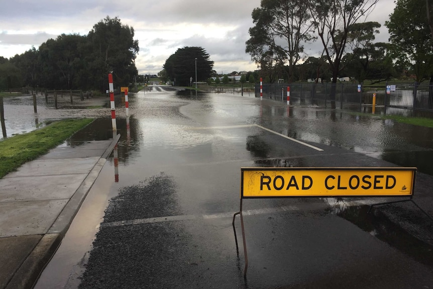 A yellow road closed sign in front of a flooded road in south west Victoria