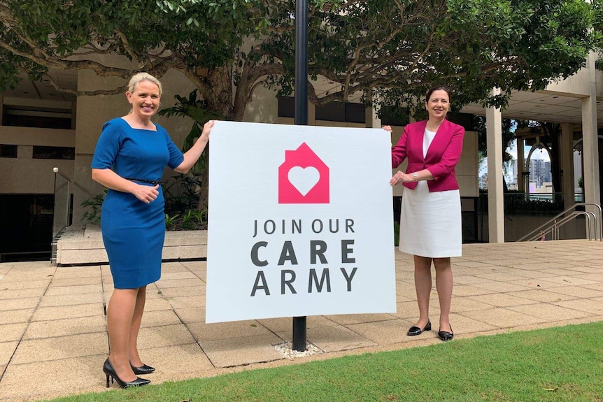 Kate Jones and Annastacia Palaszczuk stand on either side of a sign that says "join our care army'