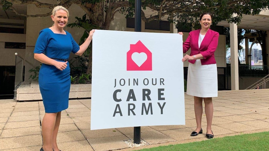 Kate Jones and Annastacia Palaszczuk stand on either side of a sign that says "join our care army'