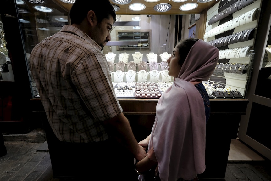 A man and woman stand in front of a jewellery store.