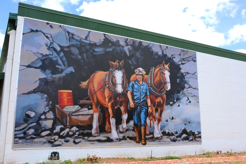A mural painted of two ponies and a mining worker walking out of a mine
