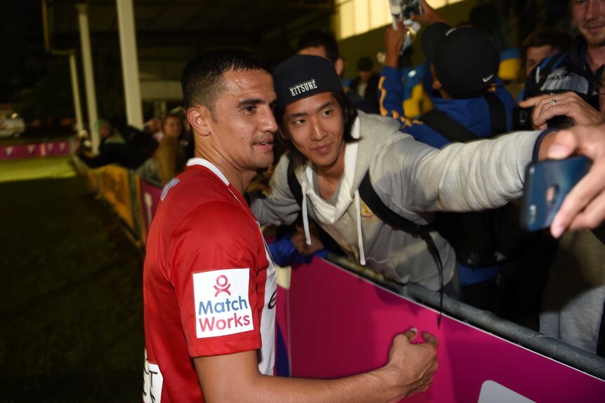 Tim Cahill poses for photo with fan