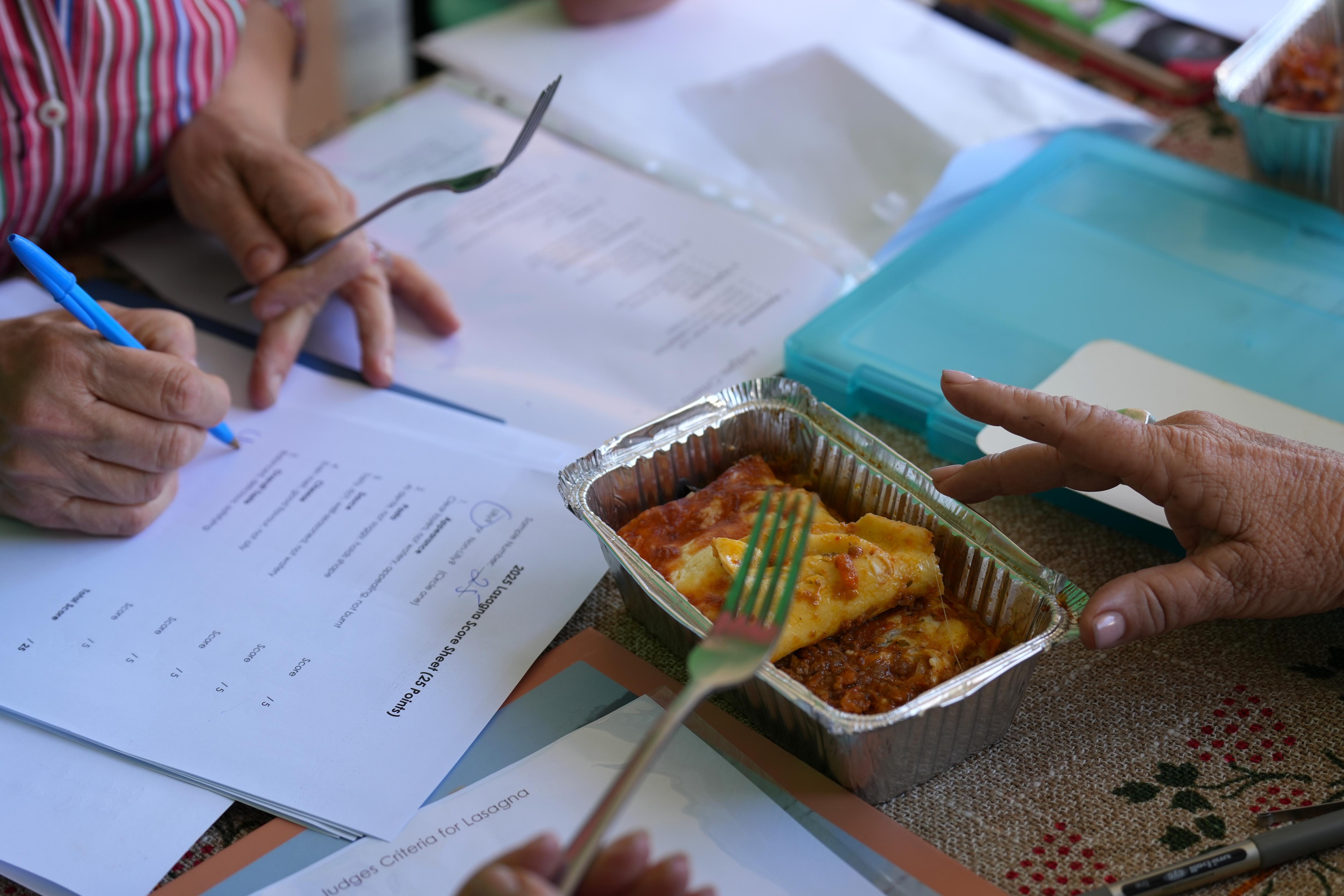 Un hombre corta un trozo de lasaña. 