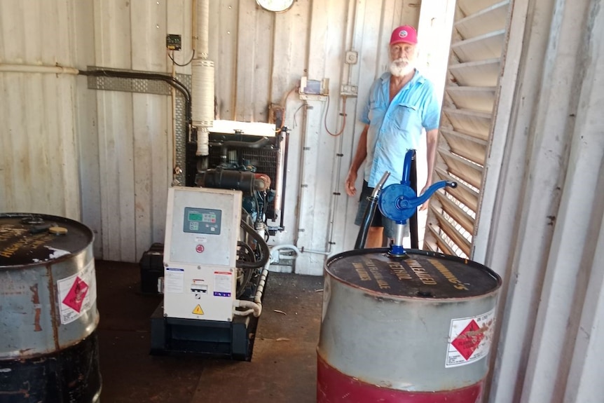 fuel drums surround a generator and a man stands in a doorway