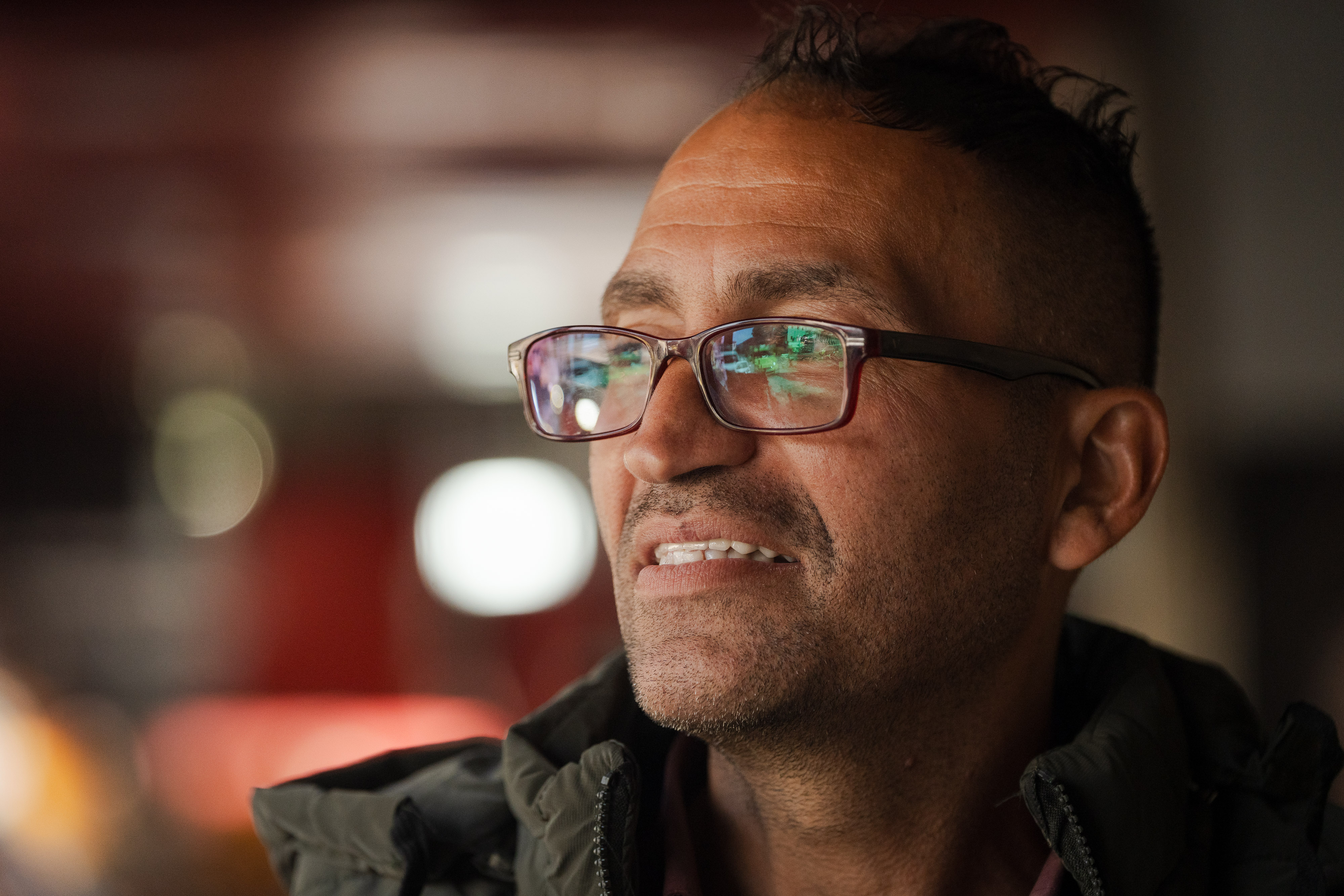 A close up of a Palestinian man wearing glasses looks over his shoulder.