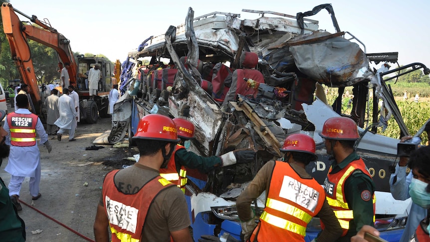 A Pakistani rescue team work on the wreckage of a deadly accident involving two buses.
