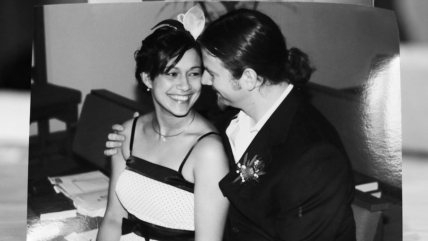 A black and white photo of a woman and man smiling at each other on their wedding day.