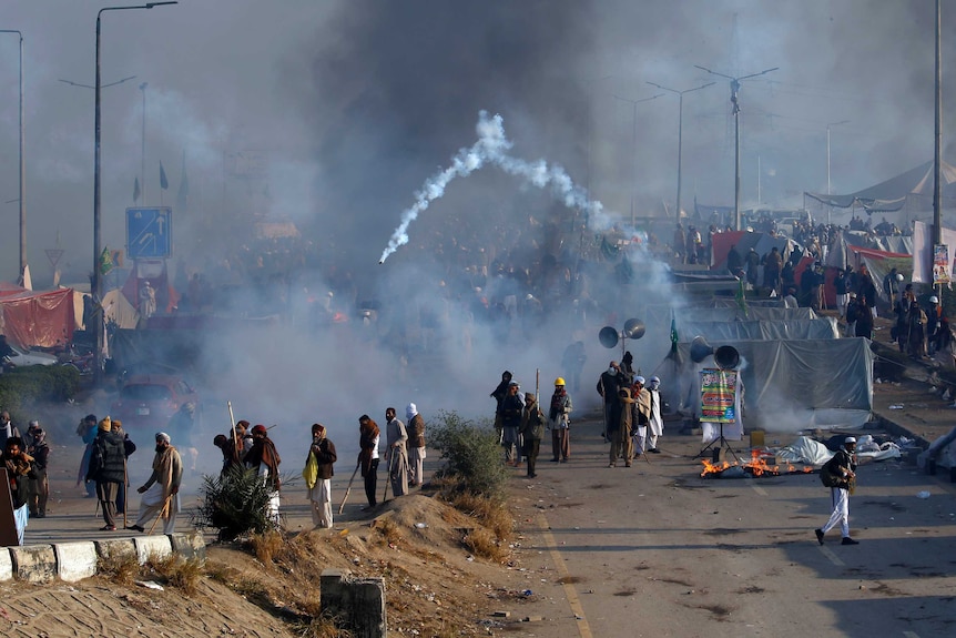 Protesters hurl back a tear gas shell fired by police during clashes in Islamabad.