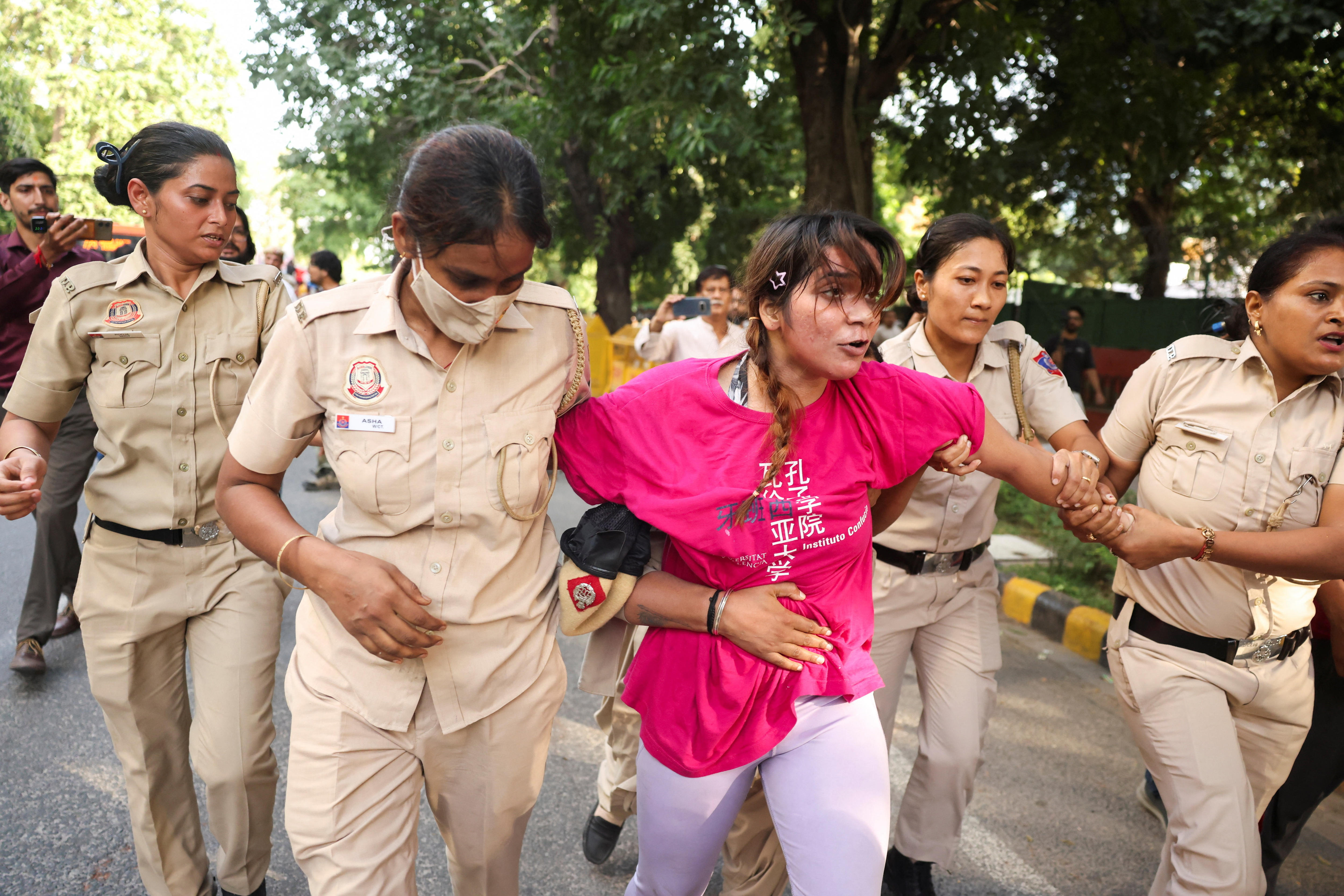 A woman being arrested by four female police officers on the streets of New Delhi.