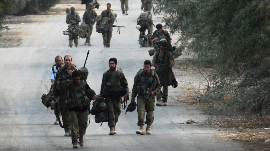 Israeli soldiers walk near the border between Israel and the Gaza Strip as they return from the Hamas-controlled Palestinian coastal enclave