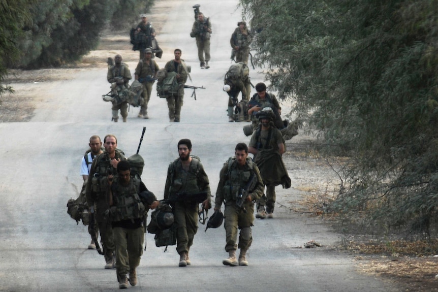 Israeli soldiers walk near the border between Israel and the Gaza Strip as they return from the Hamas-controlled Palestinian coastal enclave