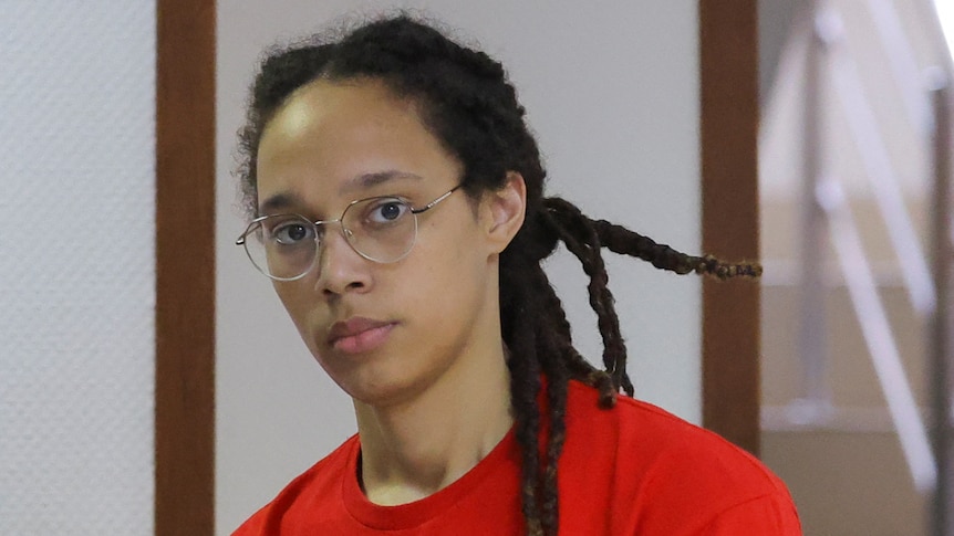 Close up of woman wearing glasses looking directly into the camera.