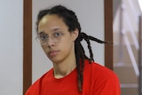 Close up of woman wearing glasses looking directly into the camera.