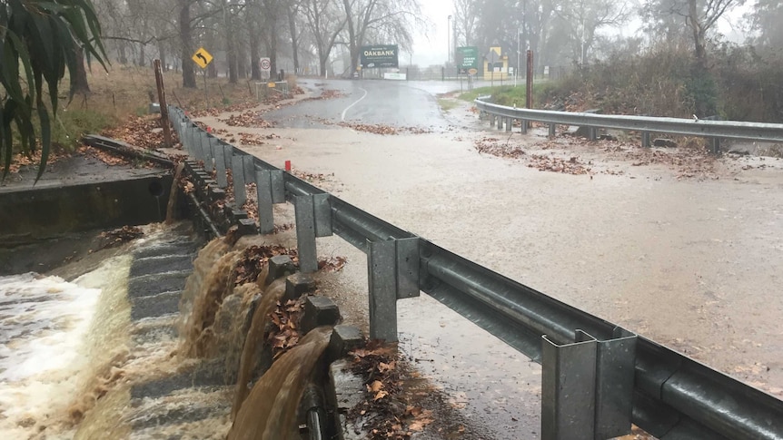 Brown water rushes over a road