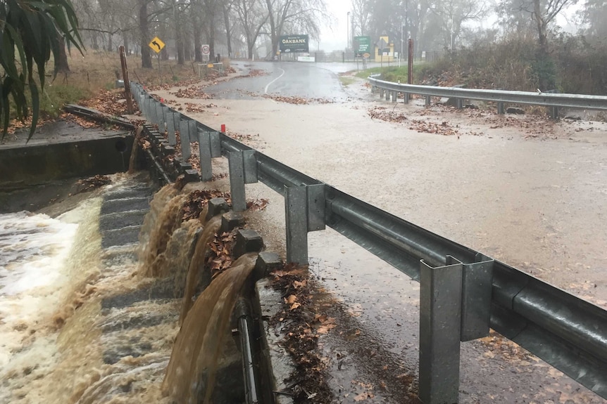 Brown water rushes over a road