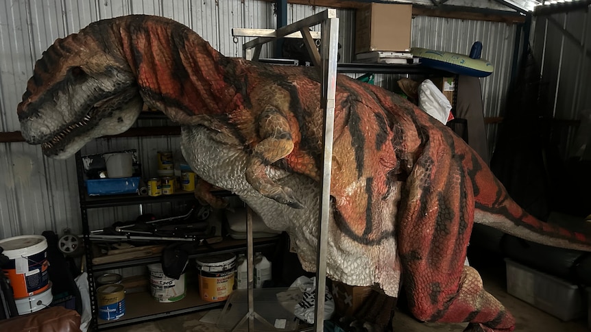A rubber and latex dinosaur suit hangs in a garage