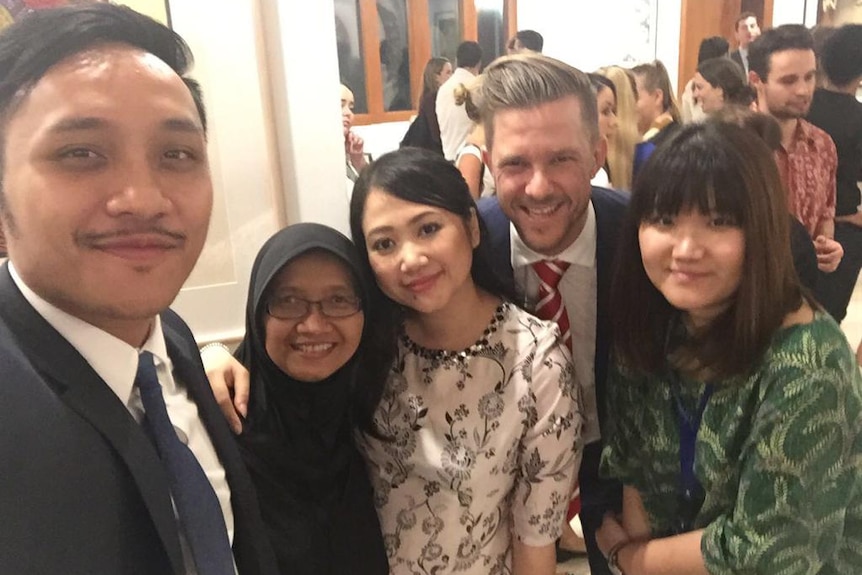 A white man in a suit poses with several Indonesians.