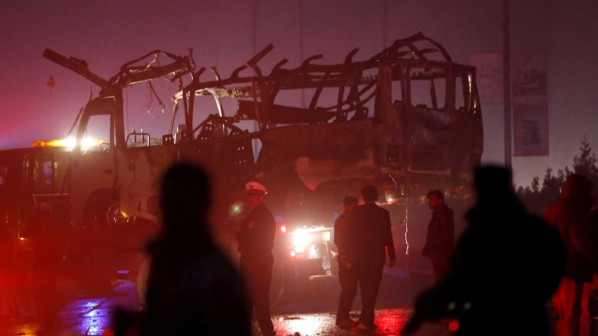 Afghan policemen and fire-fighters inspect the wreckage of the bus.