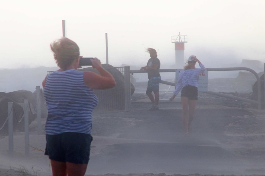 Locals are hit by wind and sand at the Spit rock wall on February 22 2019.