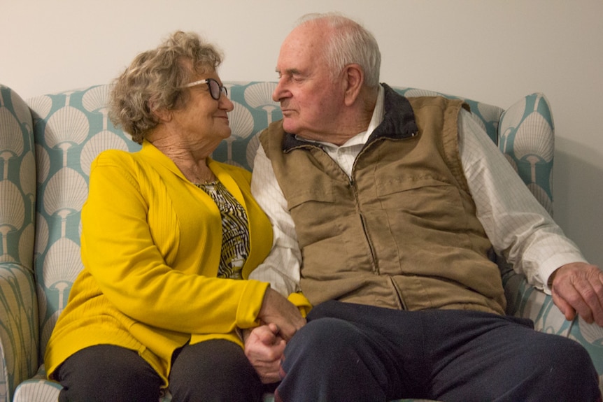 Kathleen and Joel Pickering sit together on a coach.