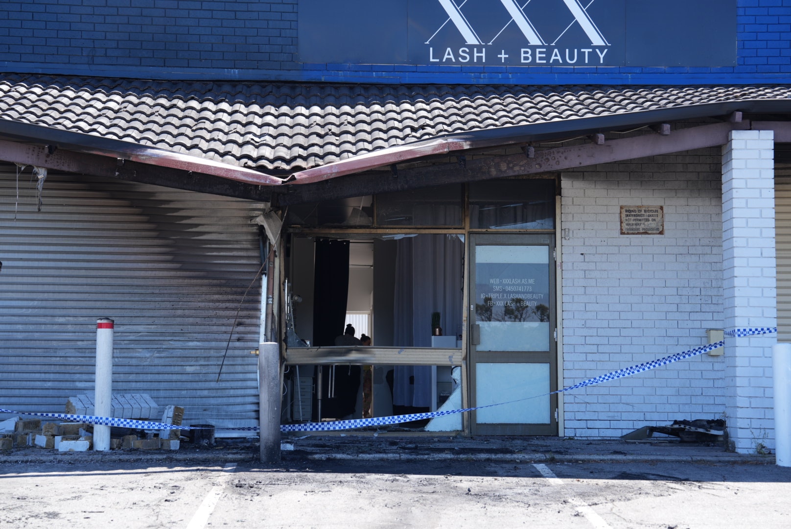 Una tienda dañada por el fuego. Un cartel dice “XXX Pestañas y Belleza”. 