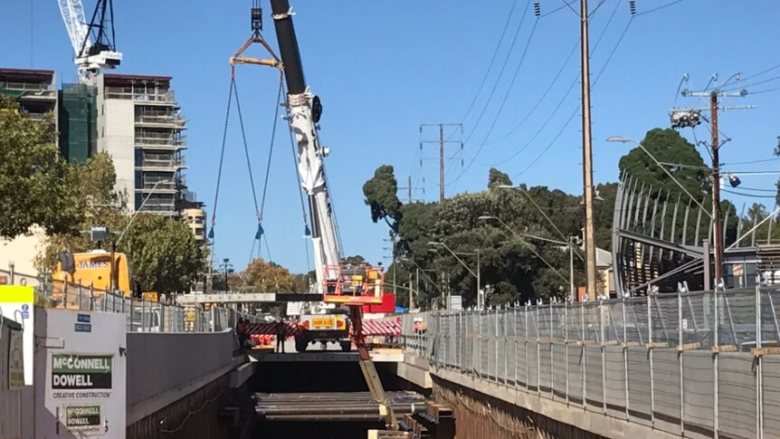 Crane lowers final roof plank into position for the Adelaide bus tunnel.