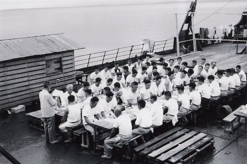 Rows of Japanese workers celebrate New Year's Day 1961 on the recovered ship The British Motorist