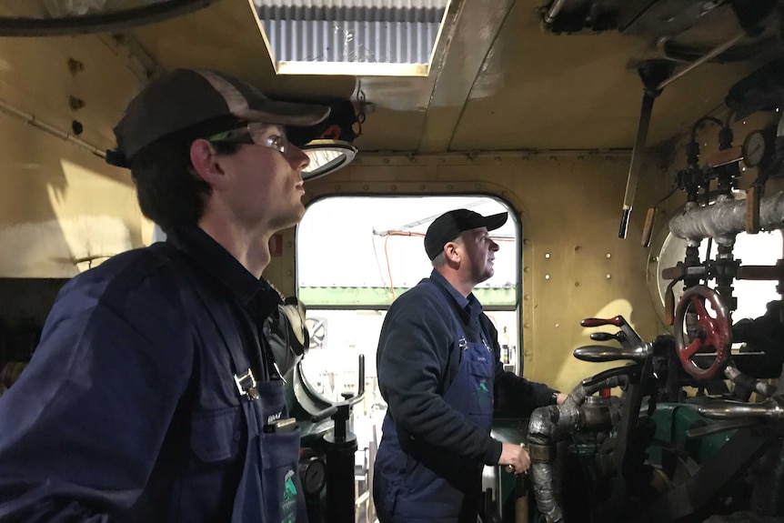 培训生布洛克·萨顿和消防员戴伦在蒸汽火车驾驶舱内进行检查。