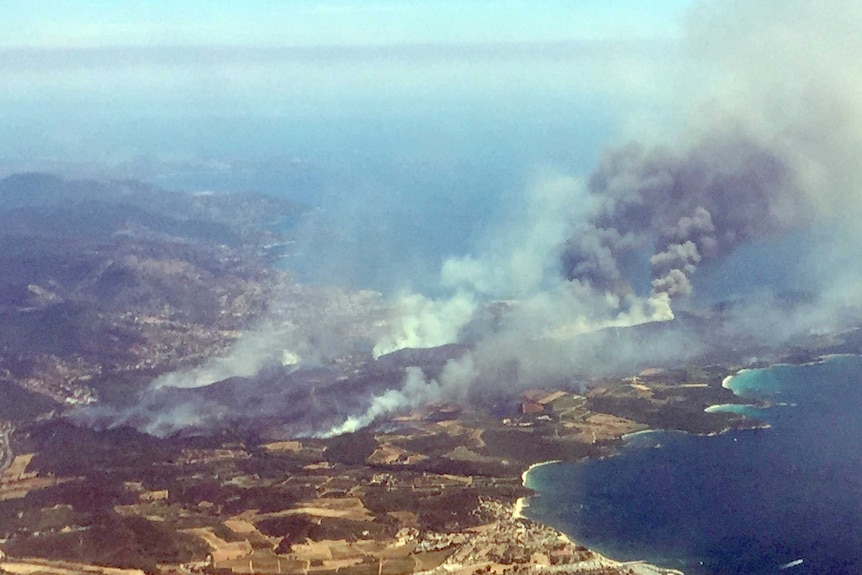 An aerial view shows plumes of smoke rising in the air from burning wildfires in the outskirts of Bormes-les-Mimosas.