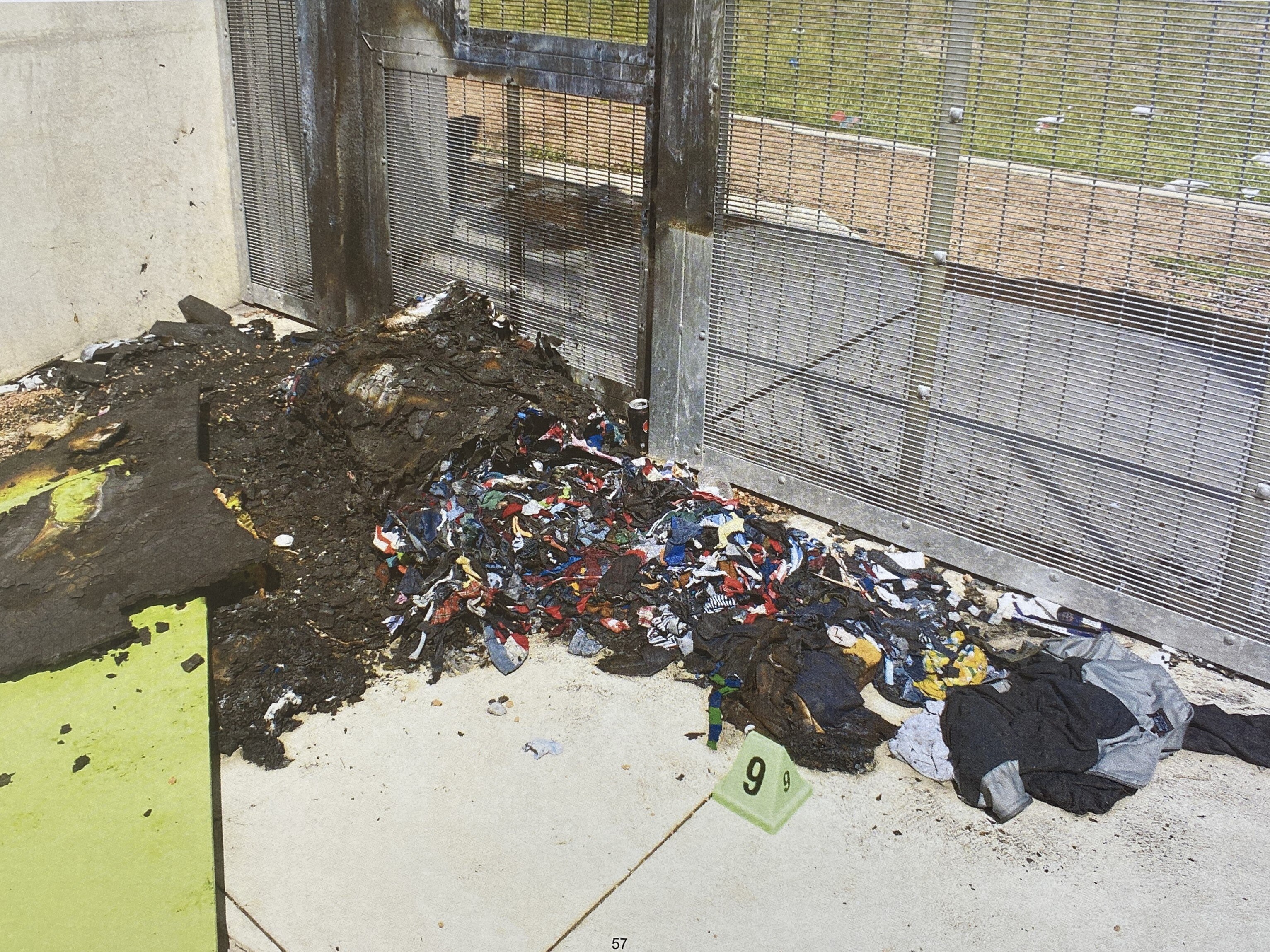 Fire damage and piled up clothes in an outdoor area of a prison.