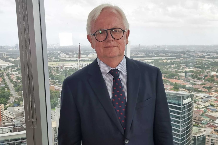 A man wearing a suit and tie and glasses.