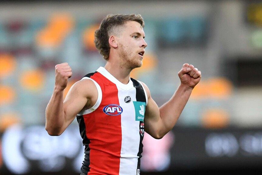 A St Kilda AFL player pumps both fists as he celebrates kicking a goal against Essendon.