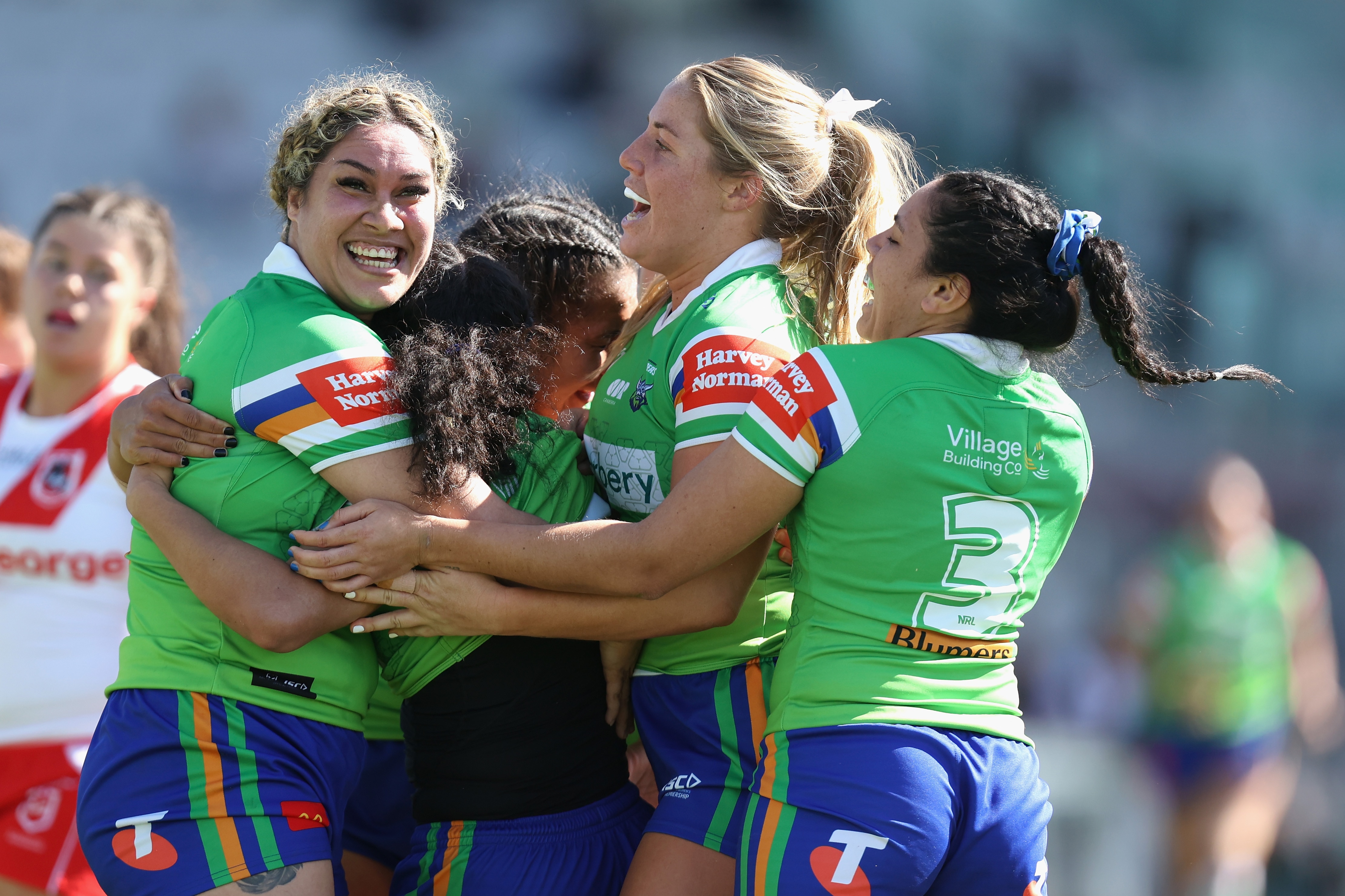 A group of Canberra Raiders NRLW players embrace as they celebrate a try against St George Illawarra.