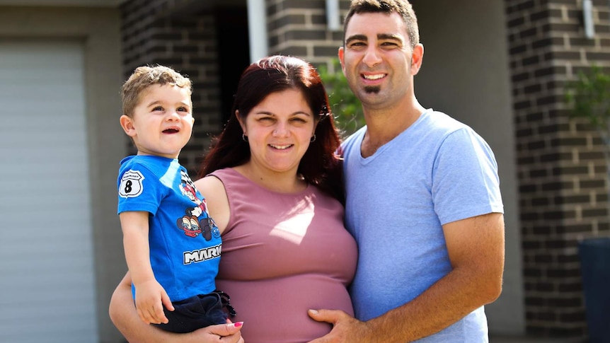 a family smiling and standing in front of the house