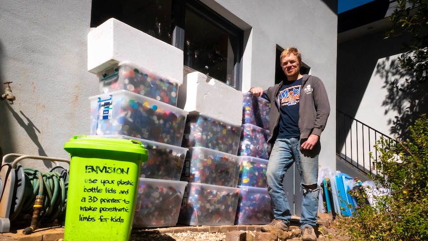 Tim Miller stands next to a dozen tubs full of plastic lids.