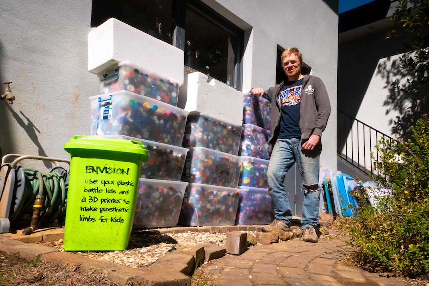 Tim Miller stands next to a dozen tubs full of plastic lids.