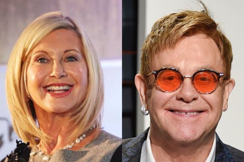 Olivia Newton-John looks slightly to the left and smiles mid-speech, with Sir Elton John on the right smiling for the camera.