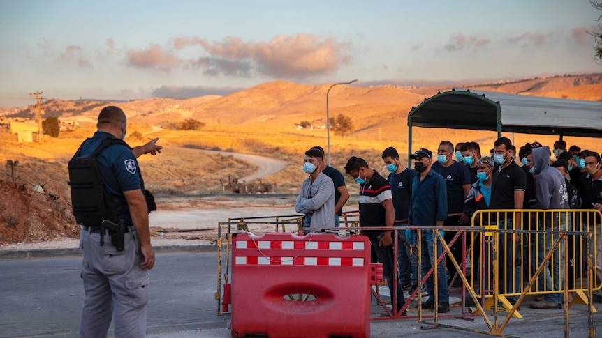 Palestinian laborers line up to cross a checkpoint at an Israeli settlement