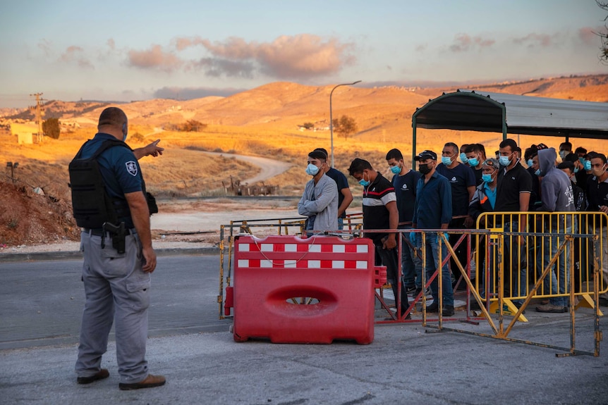 Palestinian laborers line up to cross a checkpoint at an Israeli settlement